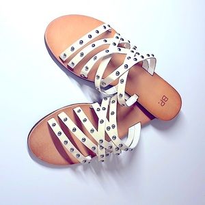 Flat cream colored sandals with metallic beading detail.